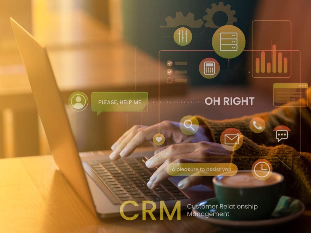 Mani su laptop con icone sovrapposte che rappresentano funzionalità CRM (calendario, email, ticketing, AI) — visualizzazione di un workspace digitale per il team vendite