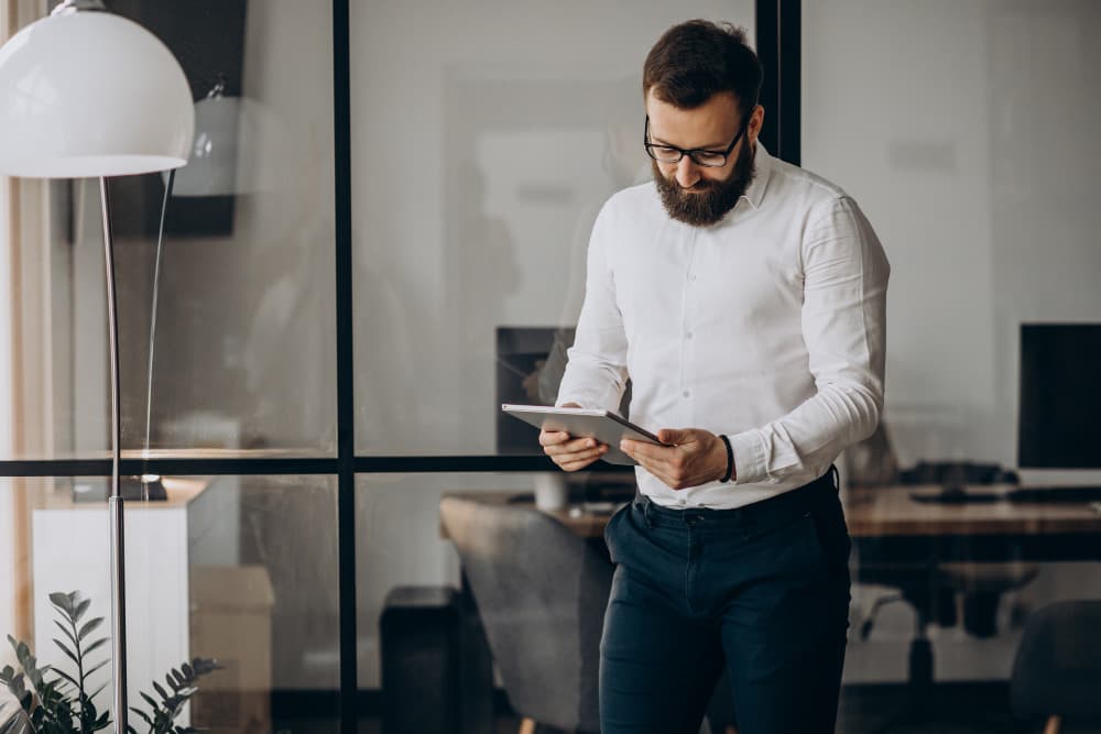 Venditore di una rete commerciale B2B consulta un CRM mobile su tablet in ufficio, schede cliente e pipeline trattative aggiornate in tempo reale
