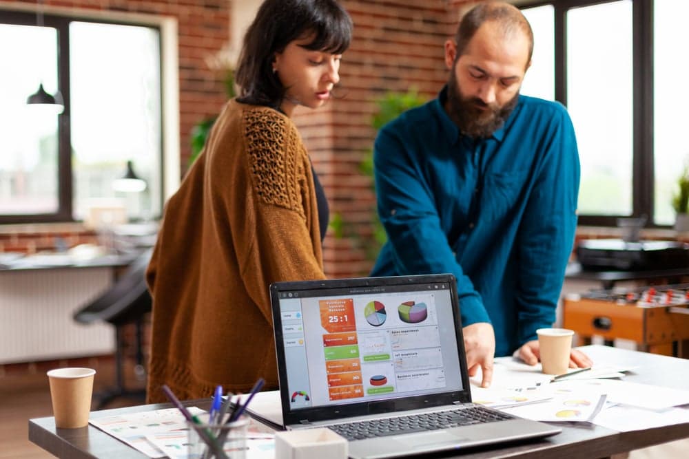 Confronto tra due dashboard CRM su schermo: HubSpot Sales Hub a sinistra e Synalla CRM a destra, con tabelle pipeline kanban e KPI di vendita visibili — alternativa italiana a HubSpot per PMI B2B