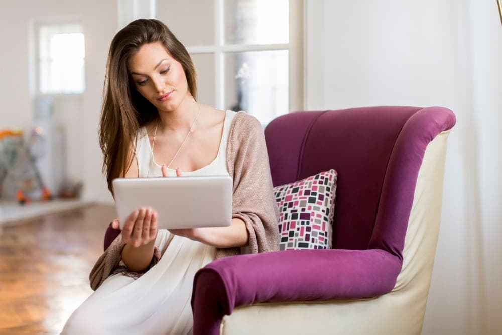Psicologa libera professionista seduta su poltrona di studio mentre rivede l'agenda clinica e la pianificazione finanziaria sul tablet