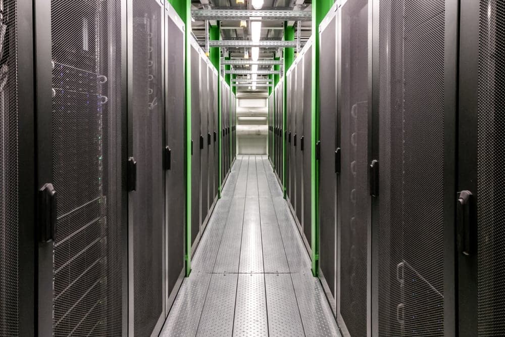 Corridoio di un data center con file di rack server illuminati da strisce verdi — visualizzazione dell'infrastruttura on-premise da confrontare con i modelli SaaS e personalizzato di un sistema CRM aziendale