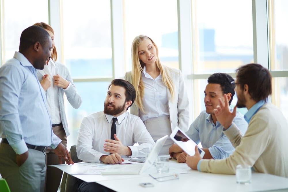 Team commerciale al lavoro in ufficio luminoso: laptop, riunione di vendita, lavagna con pipeline trattative — visualizzazione di un reparto vendite supportato da software dedicato